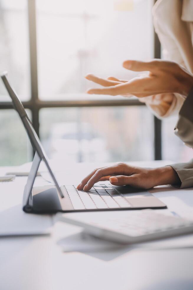 A woman is using her laptop while sitting at a desk photo