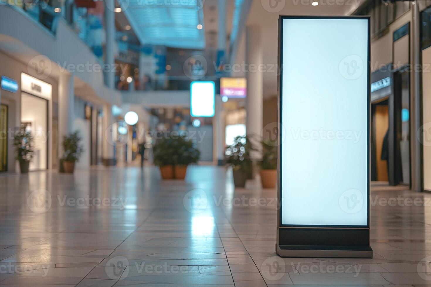 A blank advertising display in a modern shopping mall, surrounded by empty store spaces and a bright, open atmosphere. photo