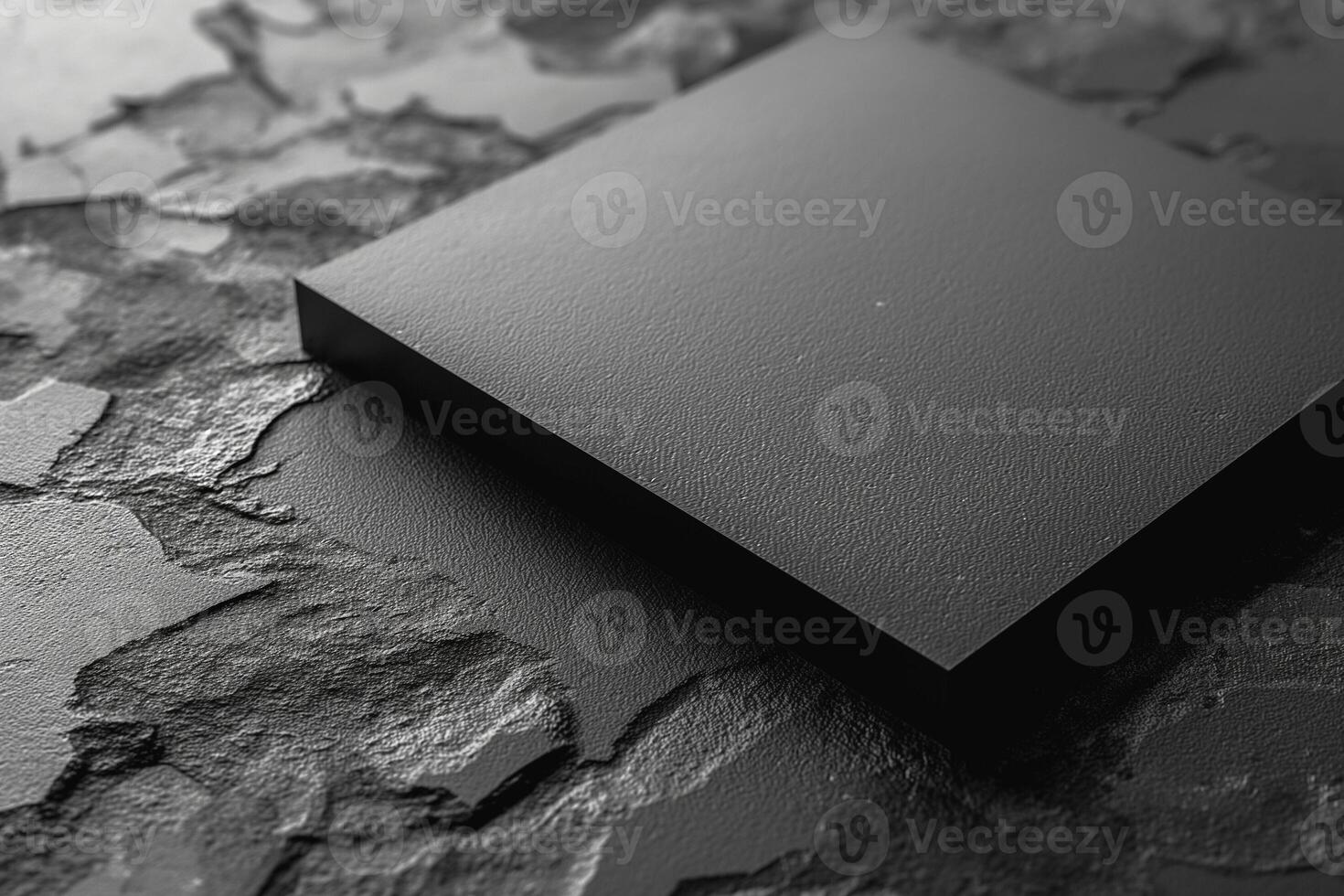 A sleek black square panel resting on a textured dark surface, creating a minimalist and modern aesthetic. photo