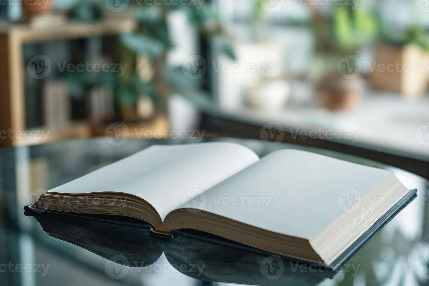 An open book with blank pages resting on a glass table, surrounded by soft greenery. photo
