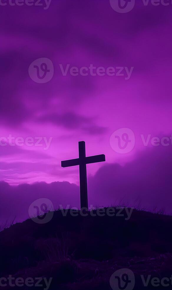 Silhouette of a Christian cross atop a hill with dramatic purple sky background, religious symbol photo