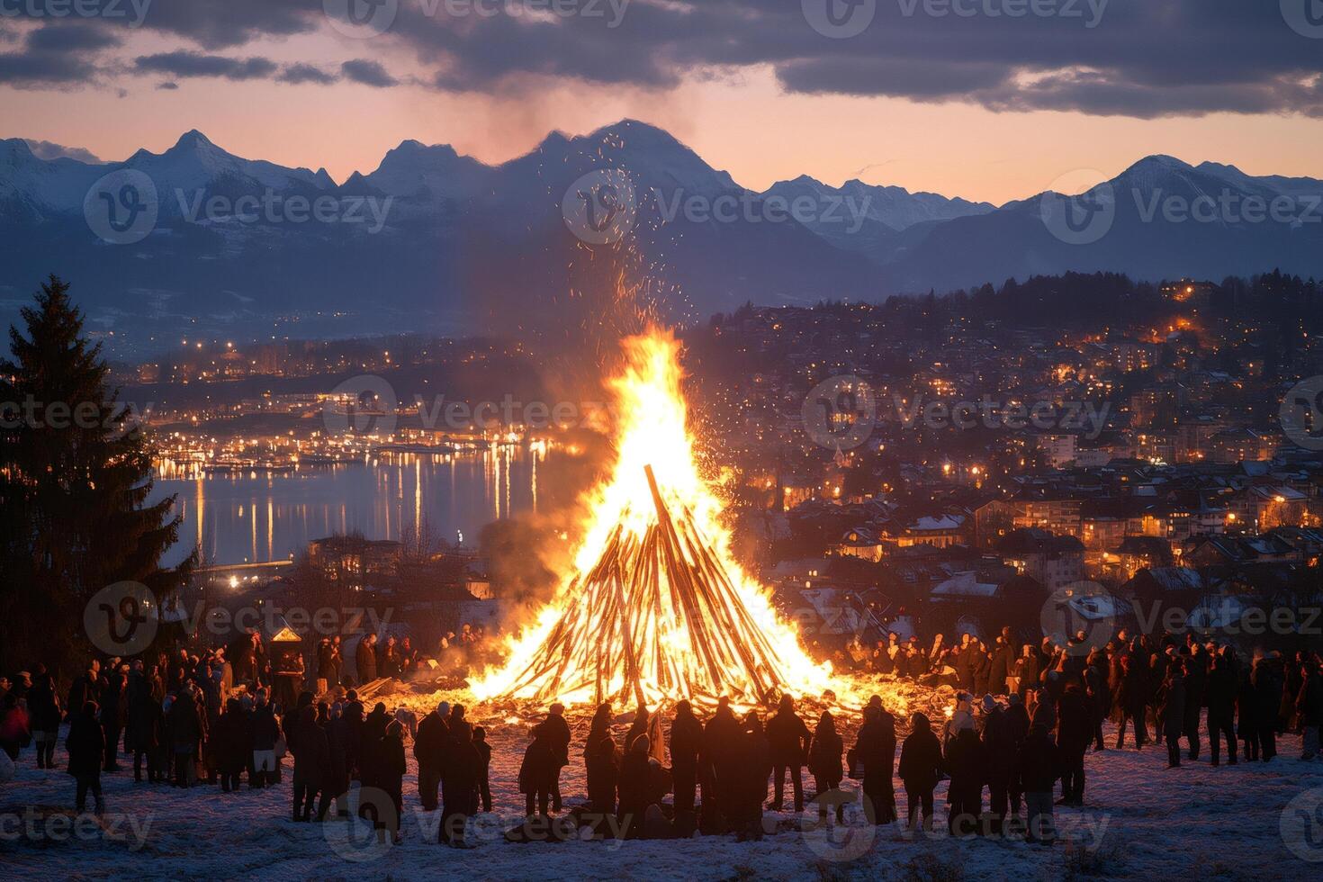 Huge bonfire burning during a winter festival in Zug, Switzerland, with snowy mountains and Lake Zug in the background photo