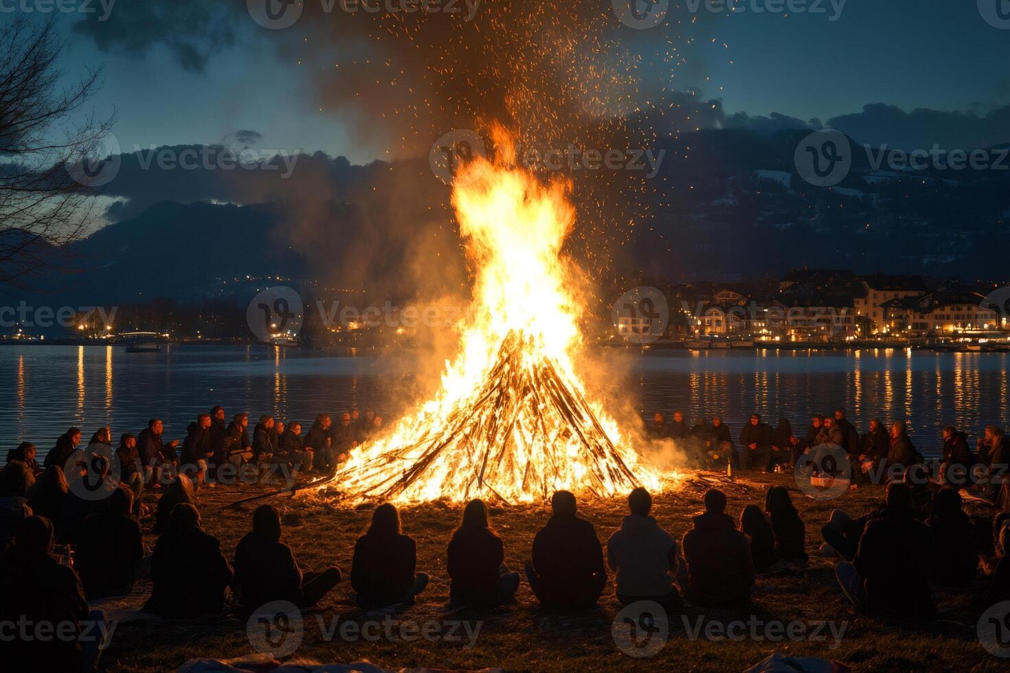 People gathering around bonfire on lakeshore at night photo