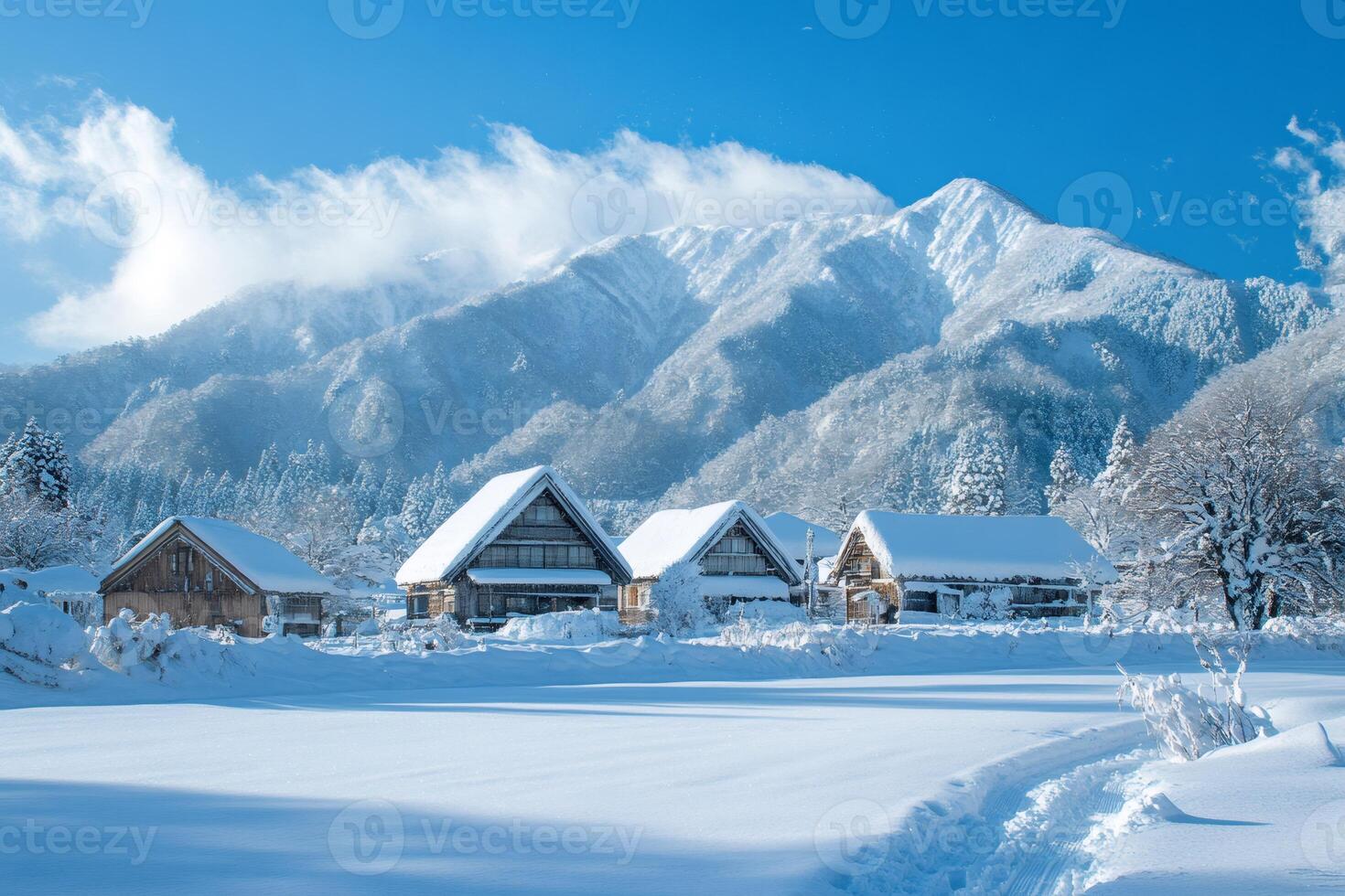 Gassho-style farmhouses standing in snowy fields with Mount Dainichi rising in the background in Shirakawa-go, Japan photo