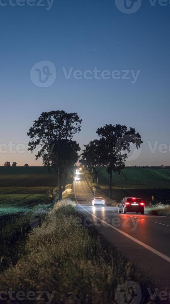 Two cars driving down a country road at night photo