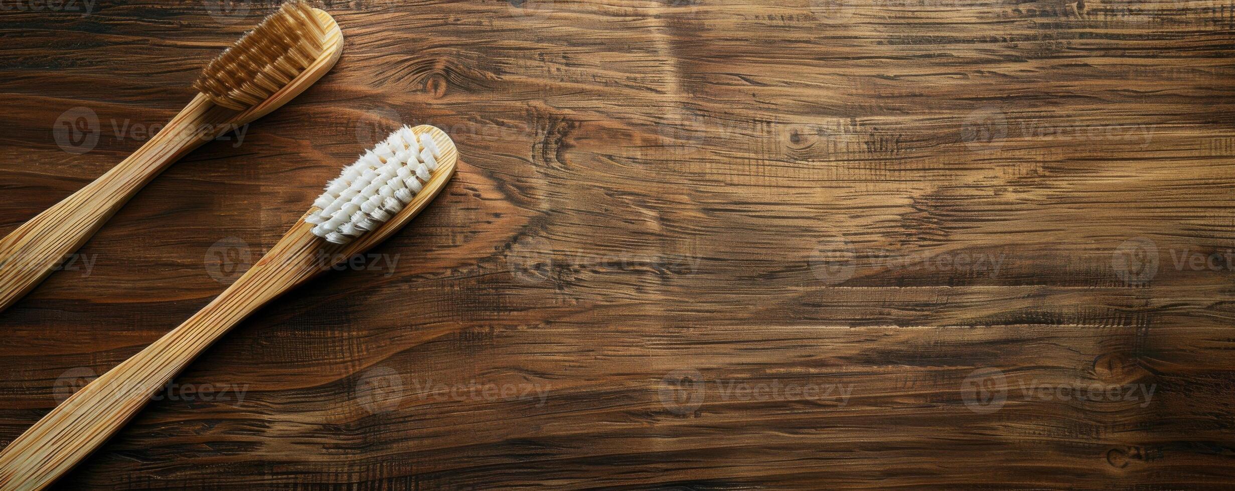 Two wooden toothbrushes rest on a rustic wooden surface photo
