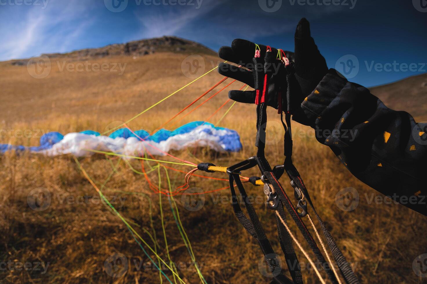 Paraglider untangles the lines of a kite before takeoff on a sunny day. Checking the sports equipment after landing on the ground photo