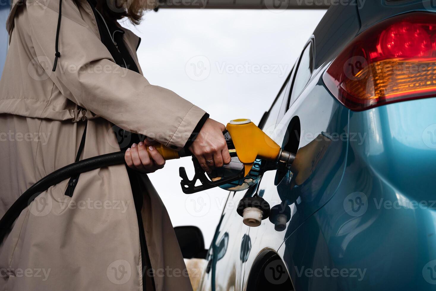 Pumping gas at the gas pump. The woman refuels the ca On a sunny day. A woman at a gas station. A woman refuels a car with gasoline at a gas station photo