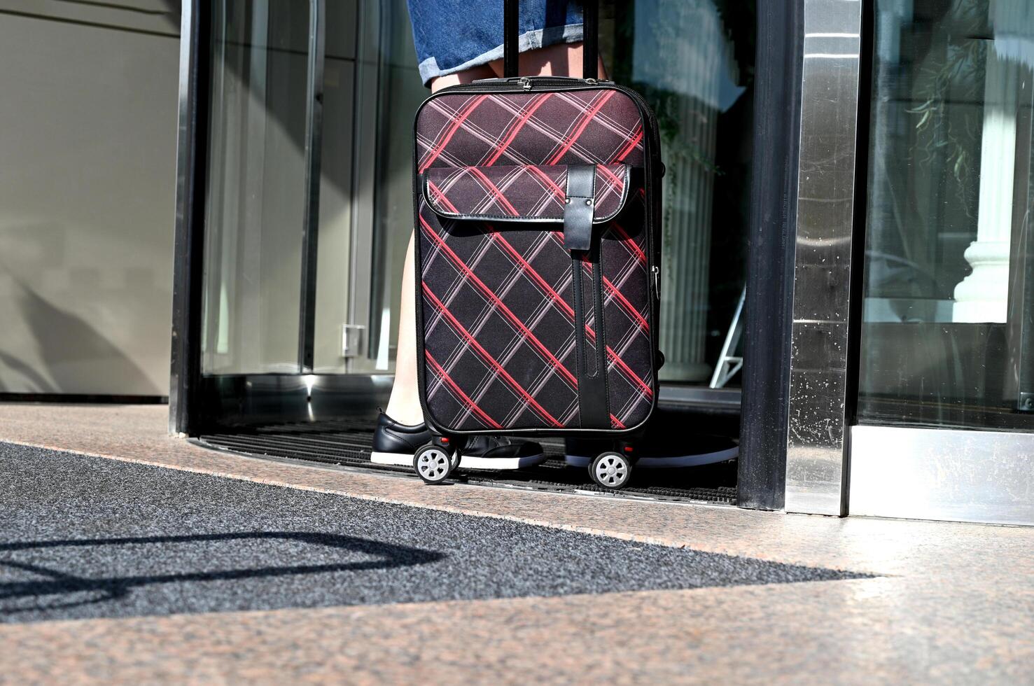 A young female traveler On a sunny day walking with a suitcase outdoors, rear view. Check-in at the hotel.The concept of urban transport and travel. photo