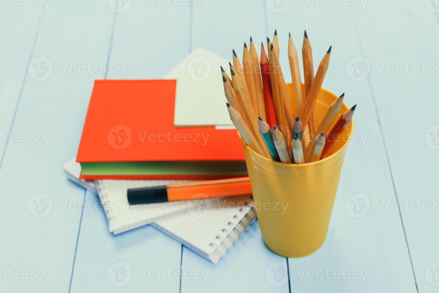 Stationery collection with colored pencils, notebooks, and sketchbooks on a light blue surface for creative activities photo
