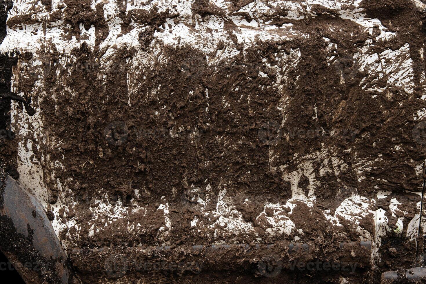 Closeup of a mud covered vehicle surface showing thick dirt layers, symbolizing offroad adventure, extreme terrain, and rugged outdoor experiences. Detailed textured view of muddy car photo