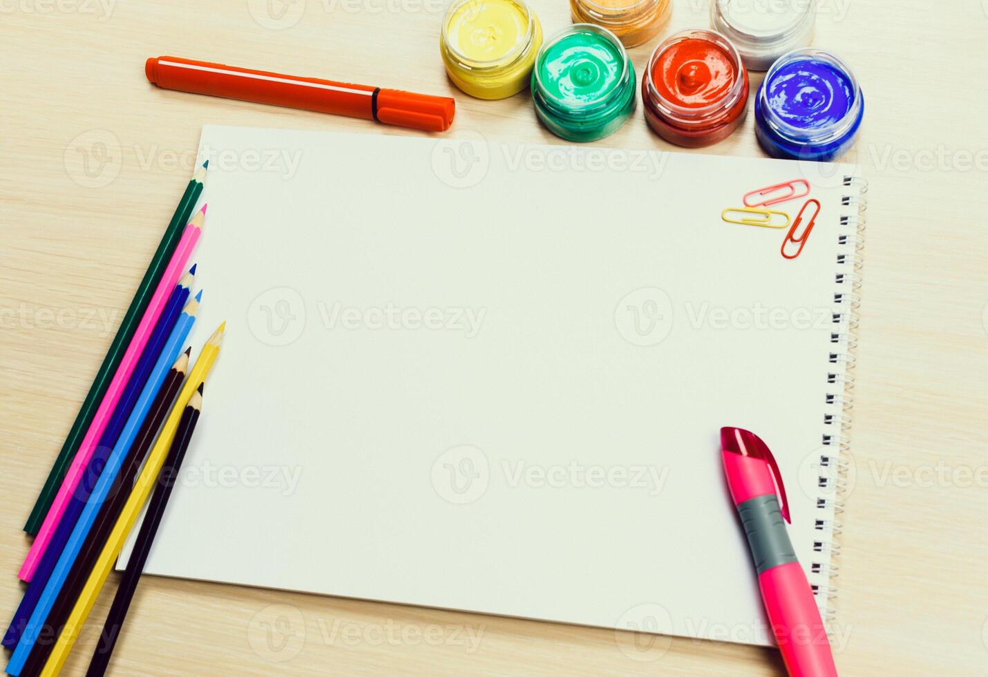 Creative workspace with blank paper, colorful markers, and paint on a wooden table photo