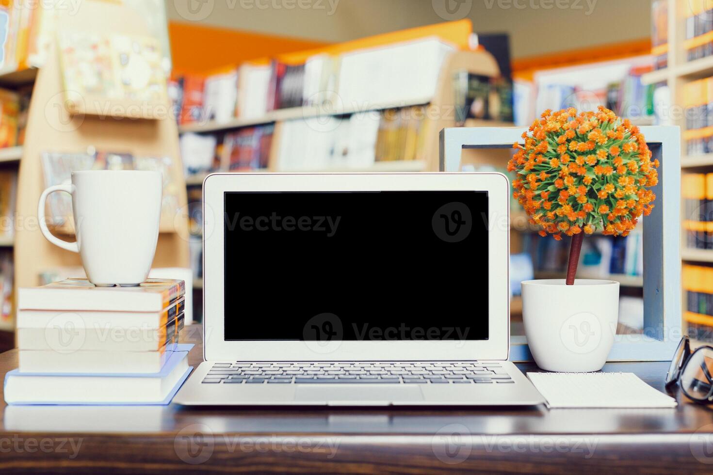 Workspace setup in a cozy bookstore with laptop, coffee, and decorative plants photo