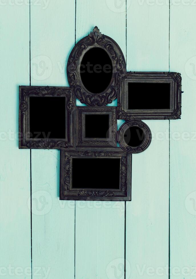 Decorative black frames arranged on a light blue wooden wall for an artistic display in a modern interior photo