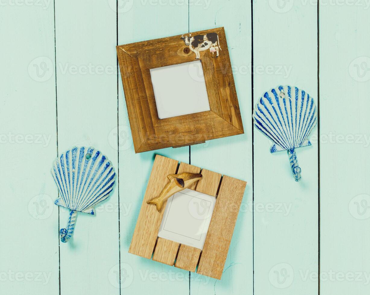 Decoratively designed picture frames and shell shapes arranged on a light blue wooden surface photo