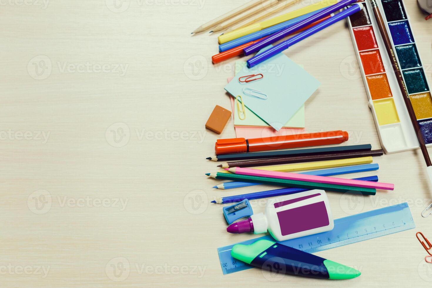 Colorful assortment of stationery and art supplies arranged on a wooden desk for creative projects photo