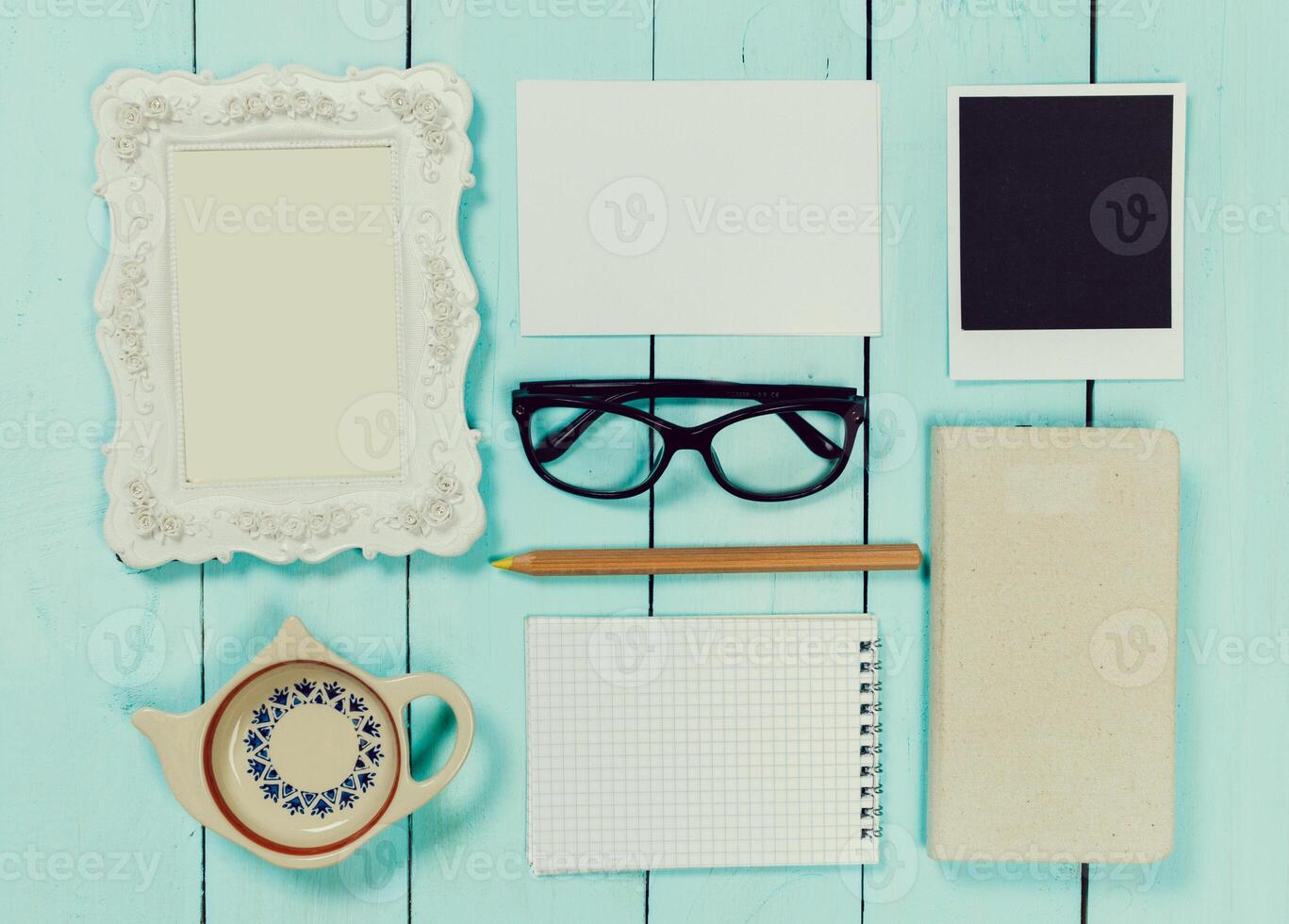 Creative workspace layout with stationery, frames, and a teapot arranged on a wooden table photo
