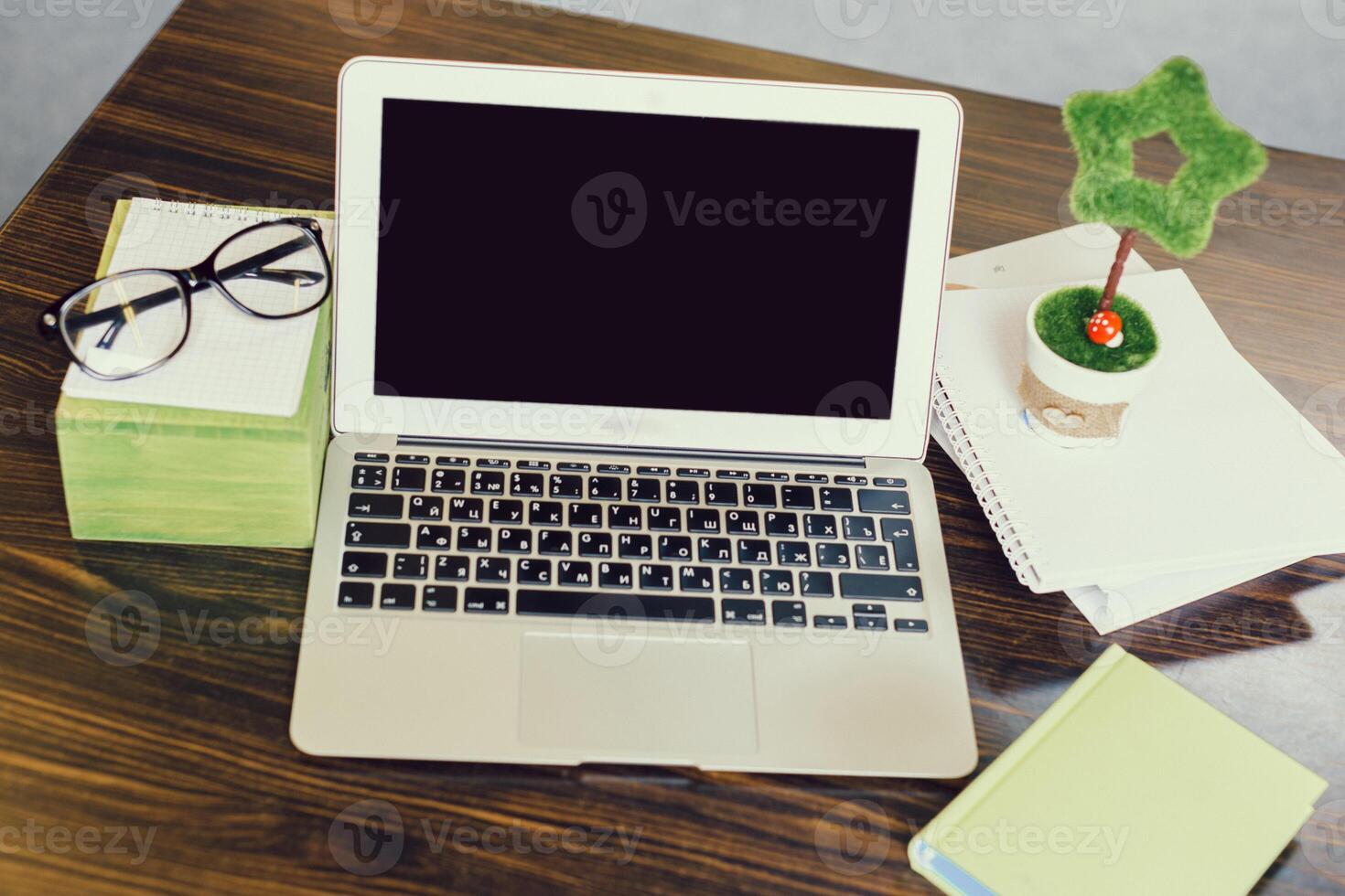 Working on a laptop at a cozy desk with green decorations and stationery during the daytime photo