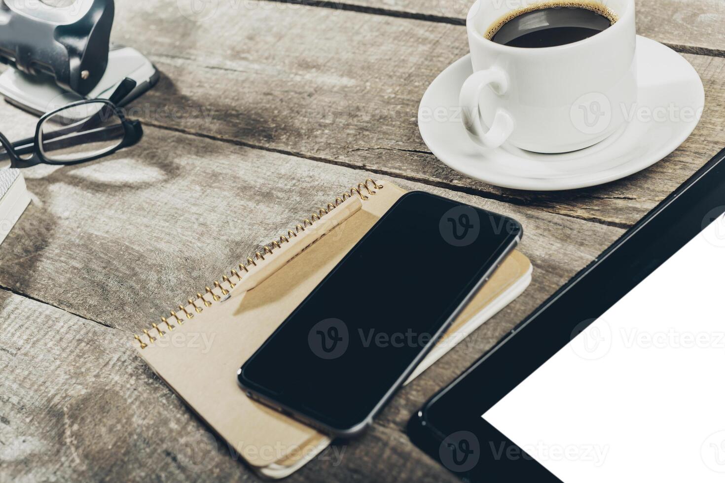 Close up of smartphone with notepad and drink on grunge wooden background photo