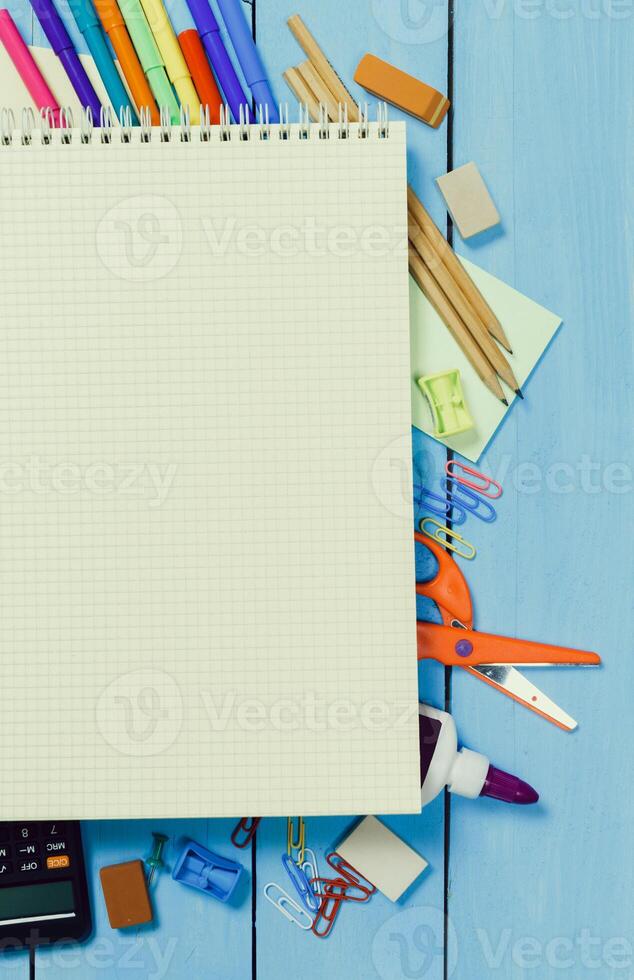 Creative workspace features blank notepad alongside colorful stationery and tools on blue wooden table photo