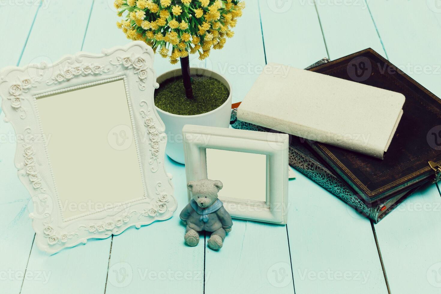 Home decor arrangement with empty frames, a teddy bear, and a small plant on a wooden surface photo