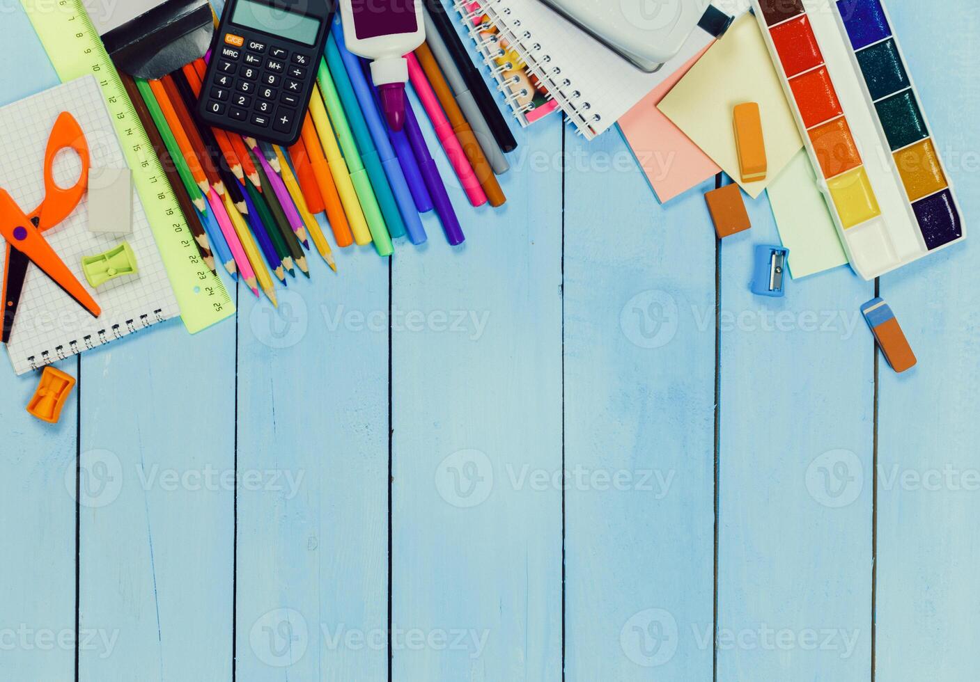 Creative workspace display with colorful stationery, art supplies, and tools on a light wooden table photo