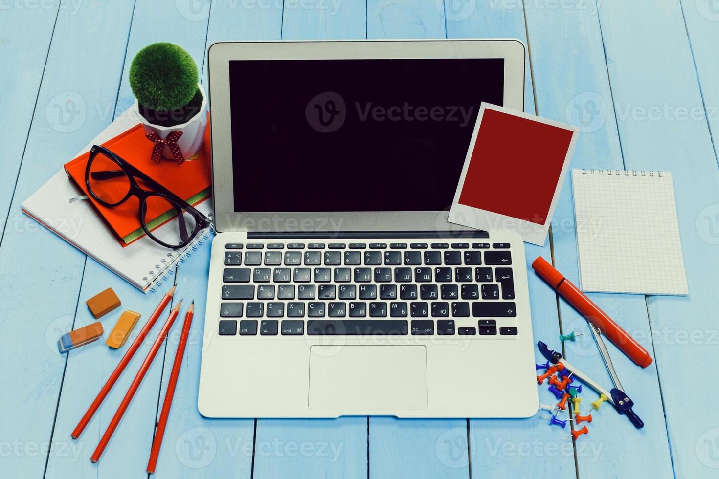 Workspace setup with laptop, stationery, and creative elements on a blue wooden table photo