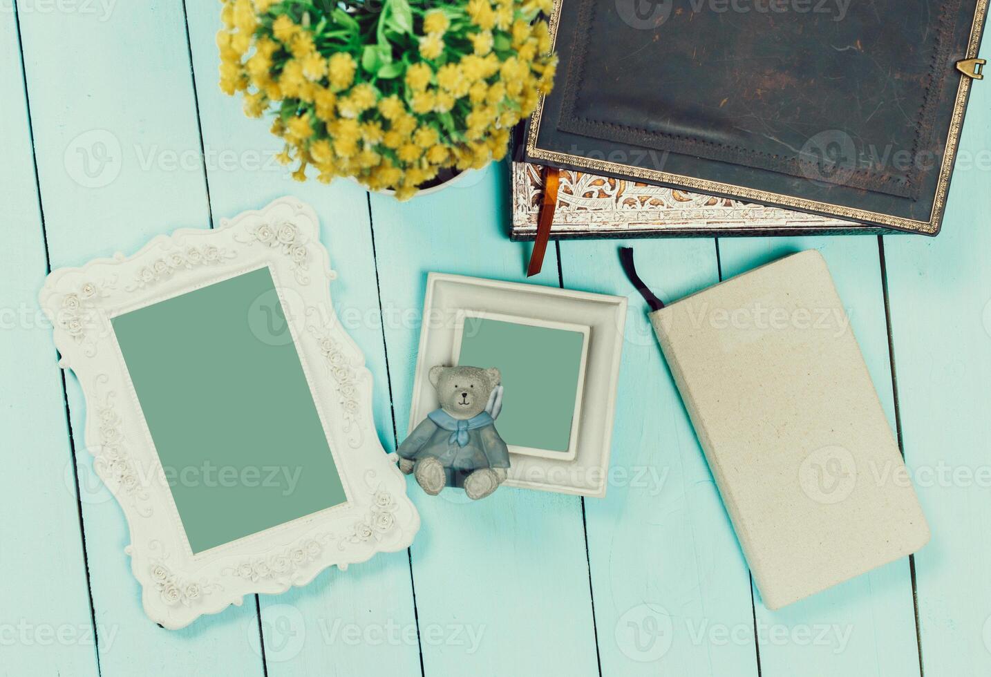 Decorative items arranged on a blue wooden table with flowers, journals, and a stuffed bear in a cozy setting photo