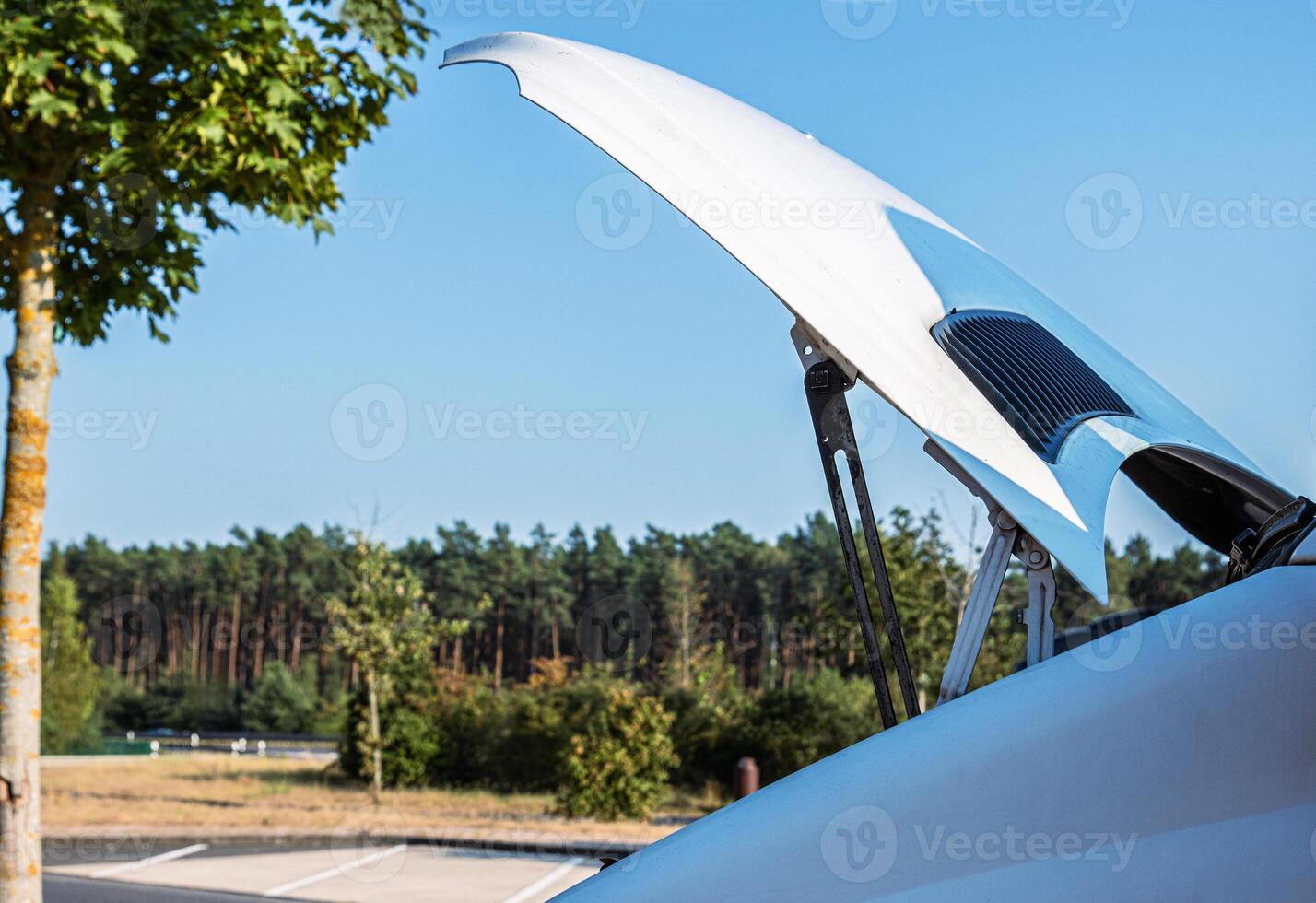 White camper van on a highway rest area with an open hood parked on a roadside for an engine check, indicating trouble or maintenance during a road trip. Copy space 2 photo