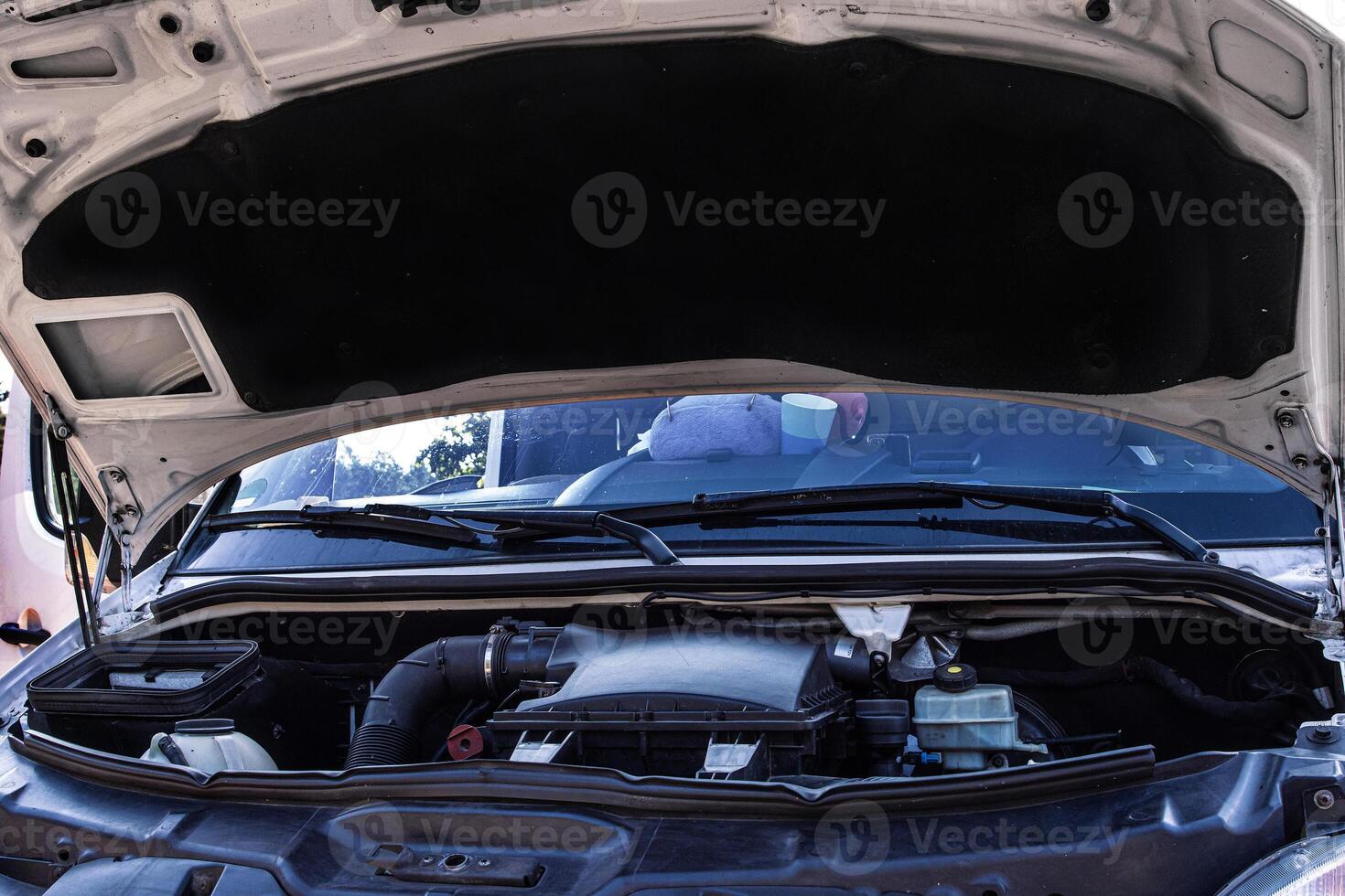 Open car hood showing engine components, vehicle maintenance, and mechanical parts. Lifted vehicle hood. Automotive repair concept with a detailed engine bay view photo