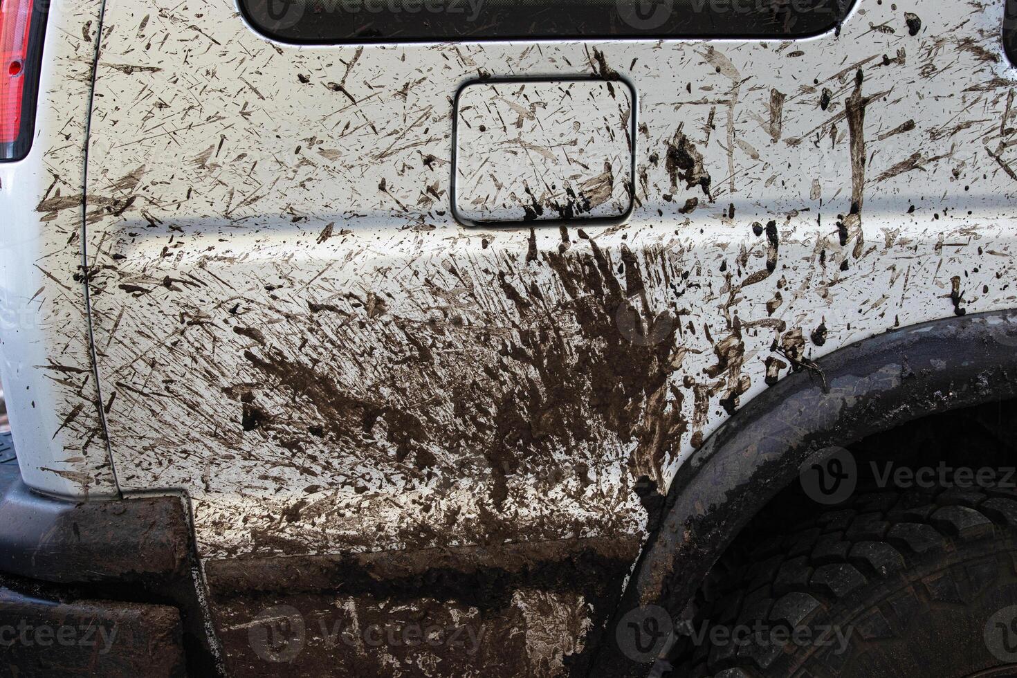 Dirty vehicle filler flap cap covered with mud splatters, wheels and tires. Closeup of a muddy car door covered in dirt. Importance of car wash, refueling, and safe driving concept 2 photo