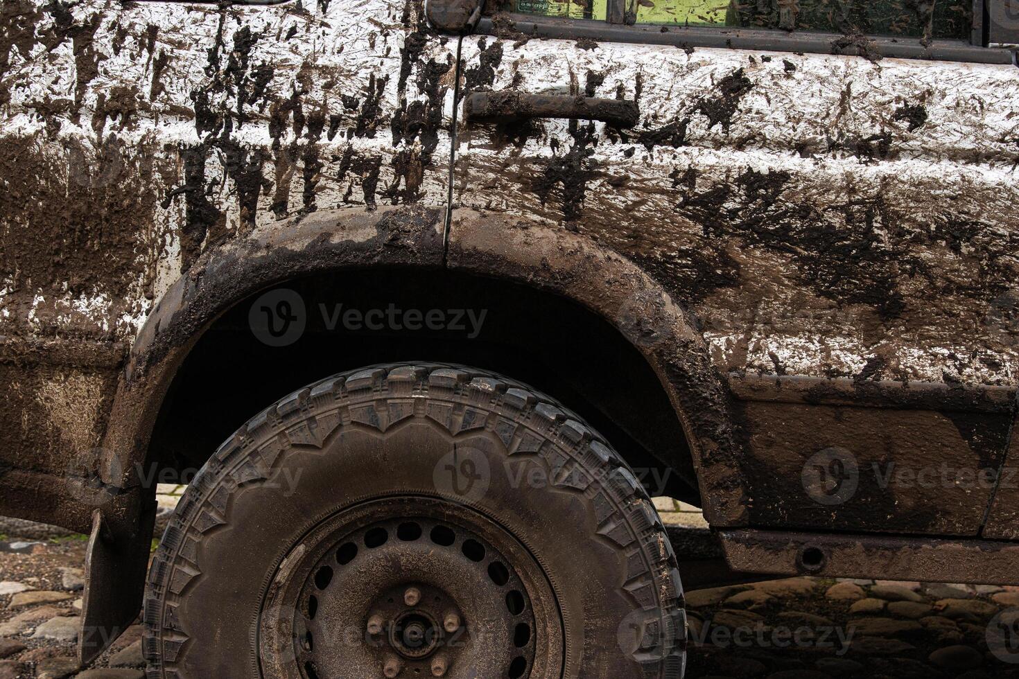 Dirty 4x4 vehicle with mud splatters on the body, wheels and tires. Closeup of a muddy offroad suv car covered in dirt. Importance of car wash, maintenance, and safe driving concept 7 photo