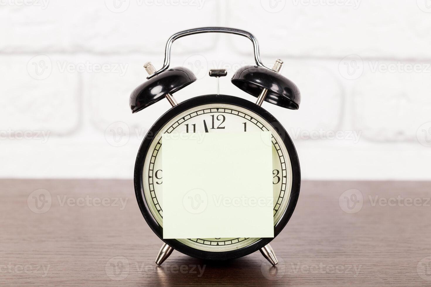 Reminder note and black old-fashioned alarm clock photo