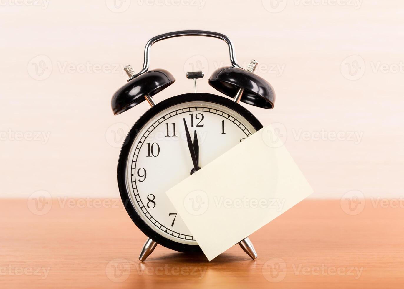 Black alarm clock on the table. Twelve o'clock photo