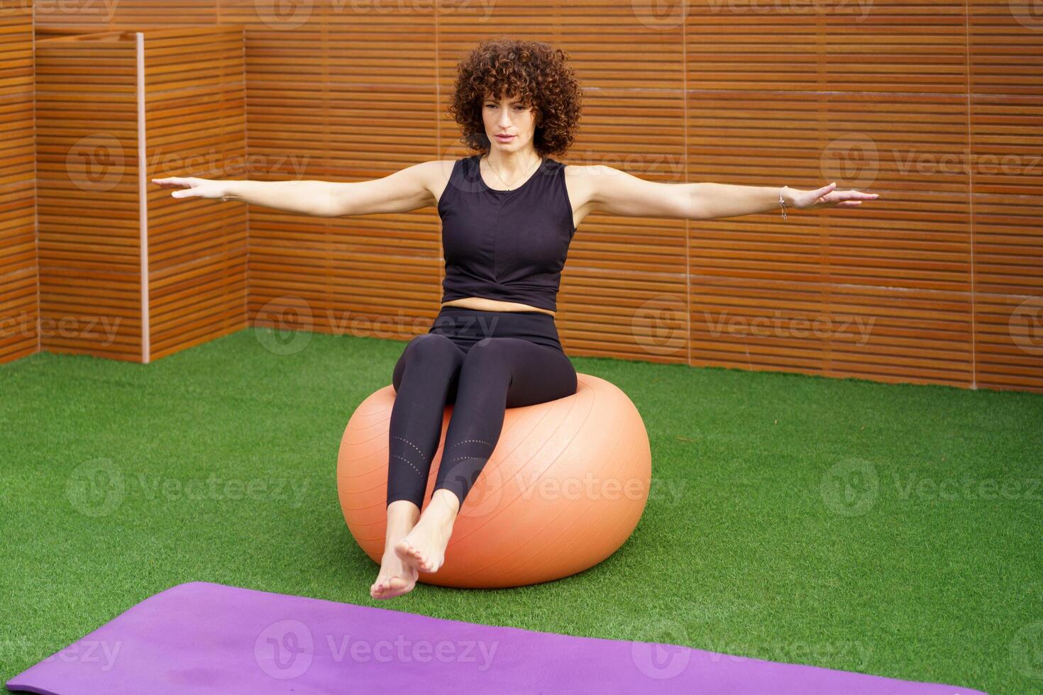 Fitness Exercise A woman expertly balancing on a stability ball within a gym setting photo