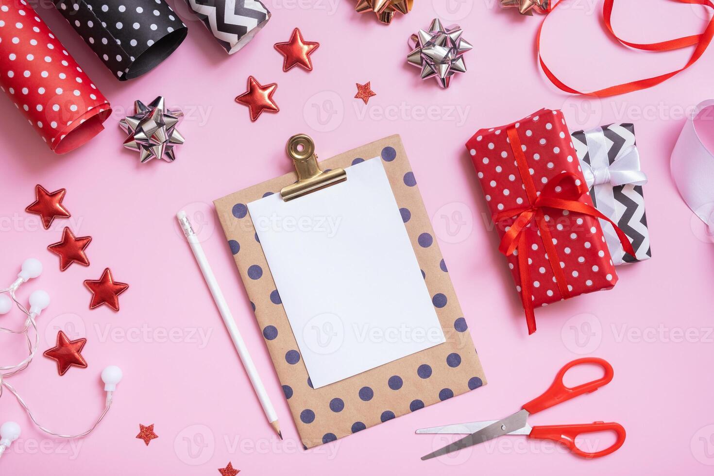 Blank sheet of paper and christmas presents with wrapping paper flat lay on pink background photo