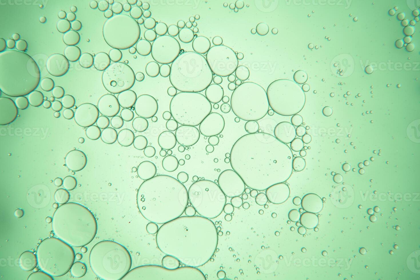 Close up view of water, bubbles and oil drops against light green background photo