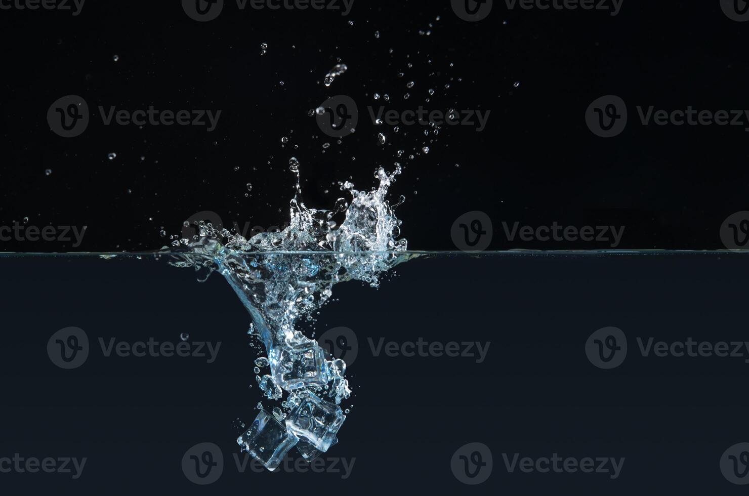 Clear ice cubes dipping into water causing a splash photo