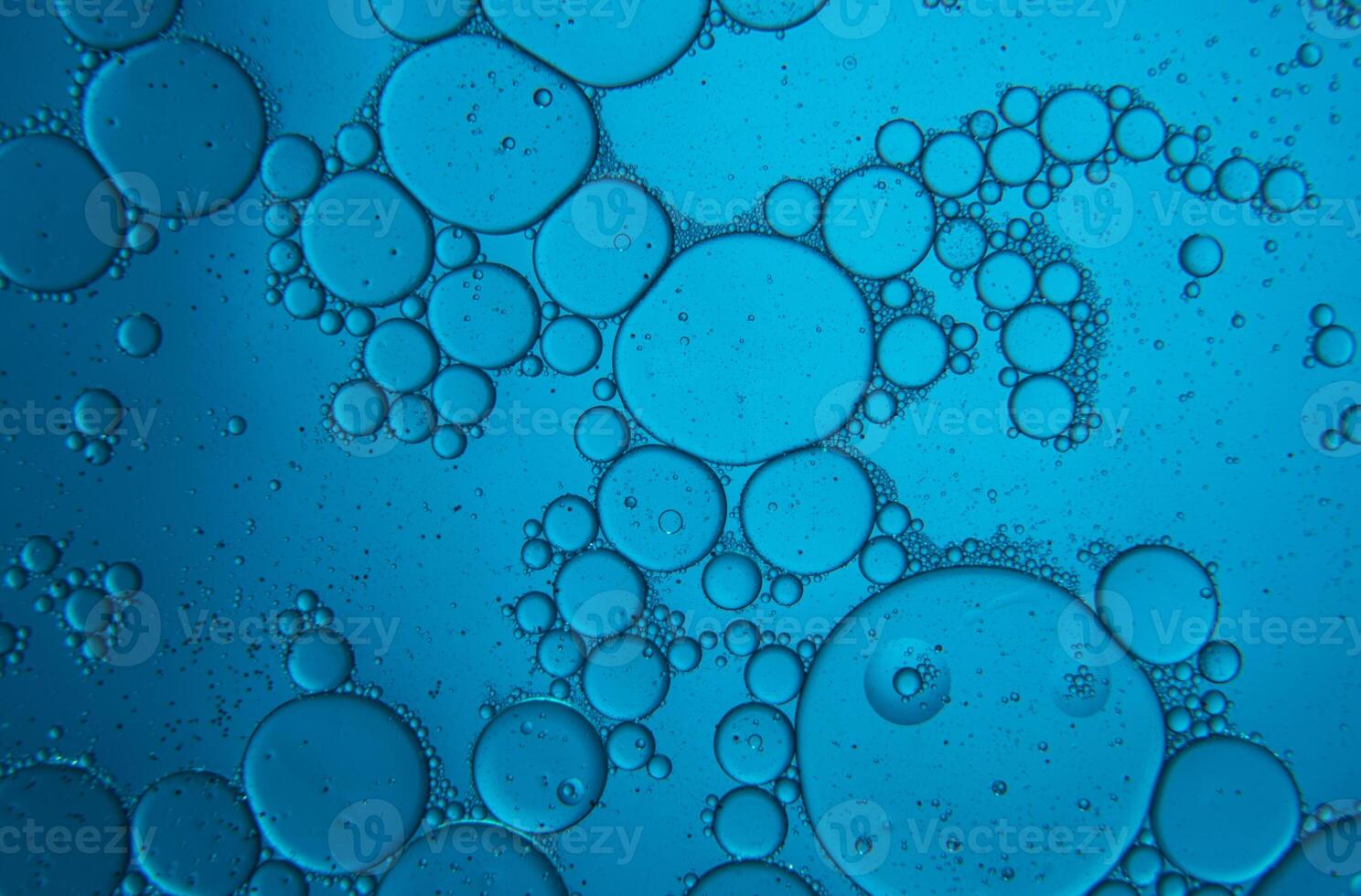 Abstract composition with water and oil drops against blue background photo