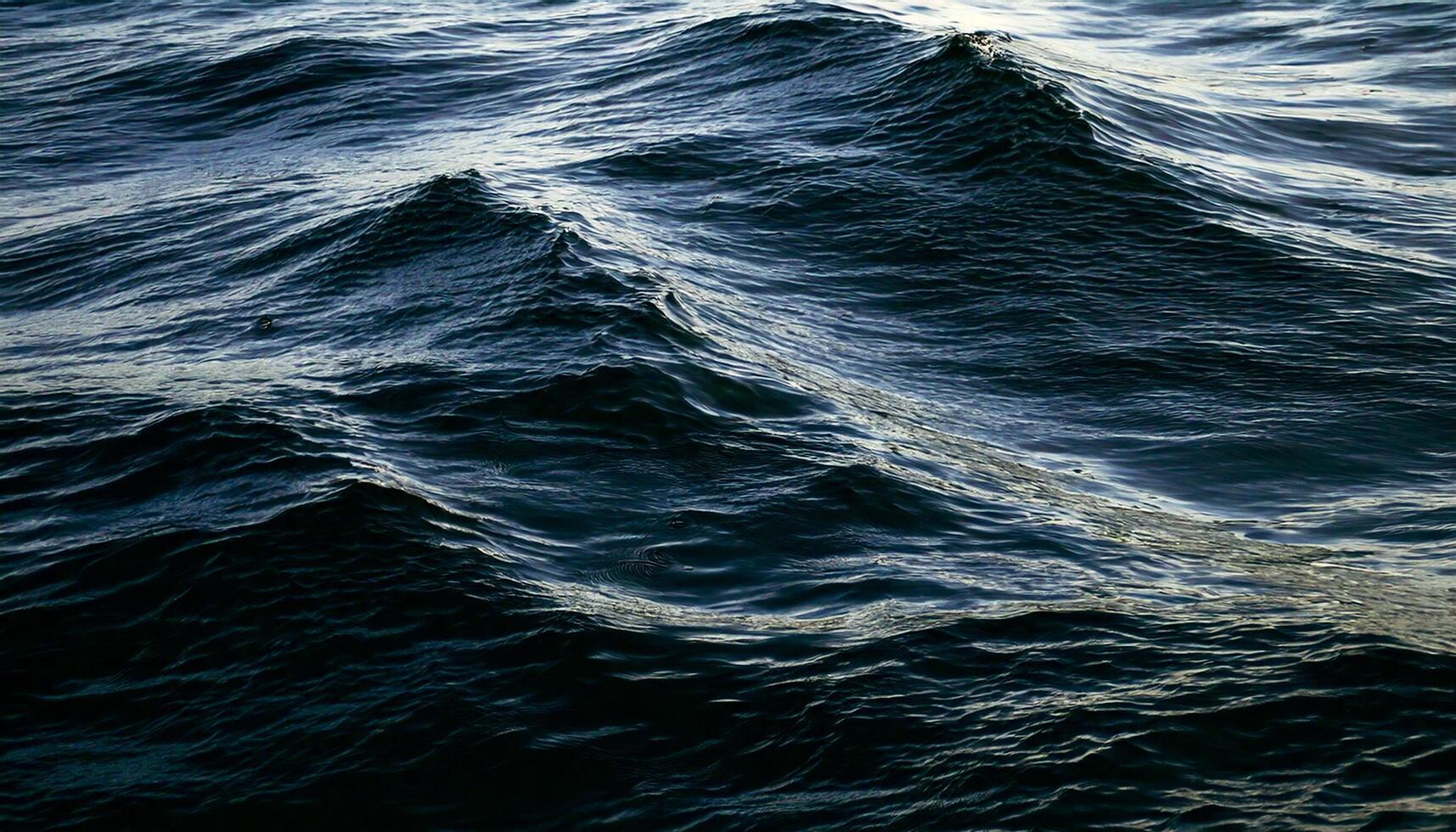 Oil black ocean water, calm except for small irregular patterns of peaks and ripples photo