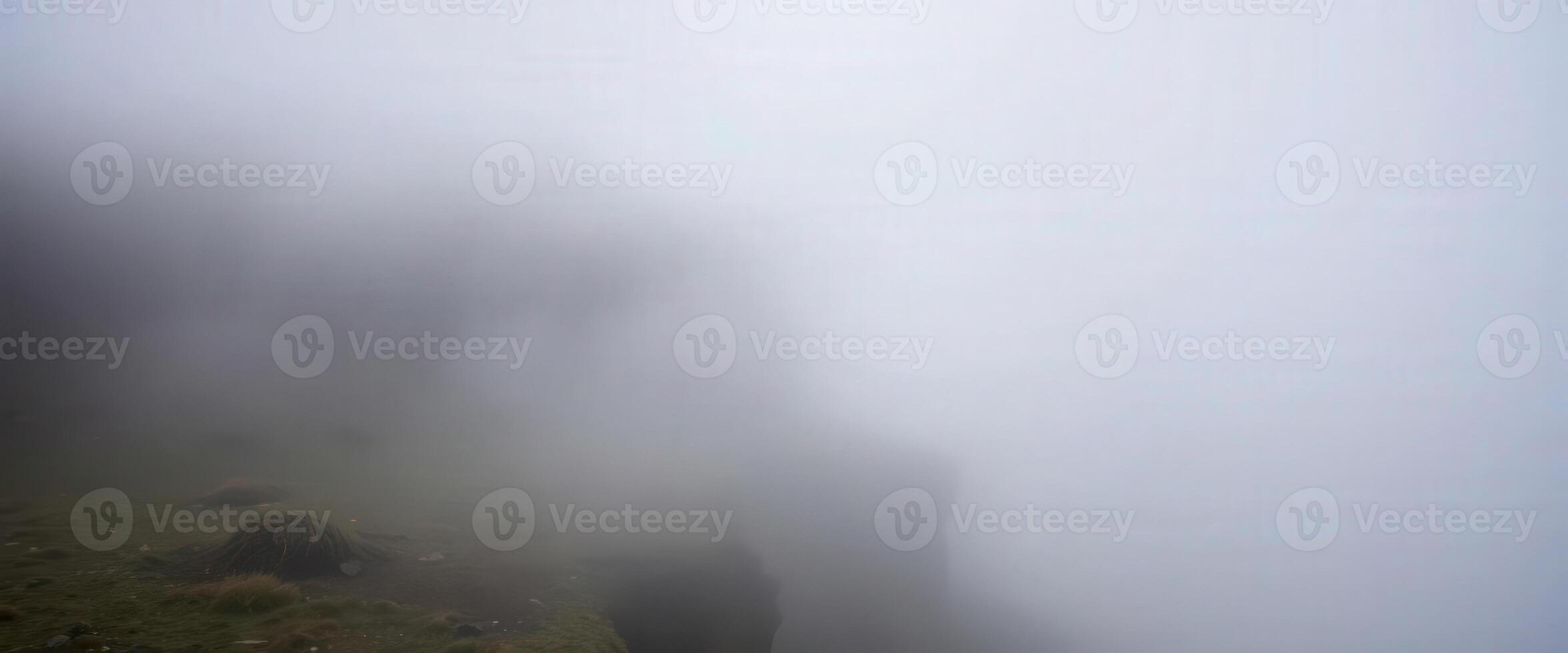 A foggy mountain with a grassy hill in the background photo
