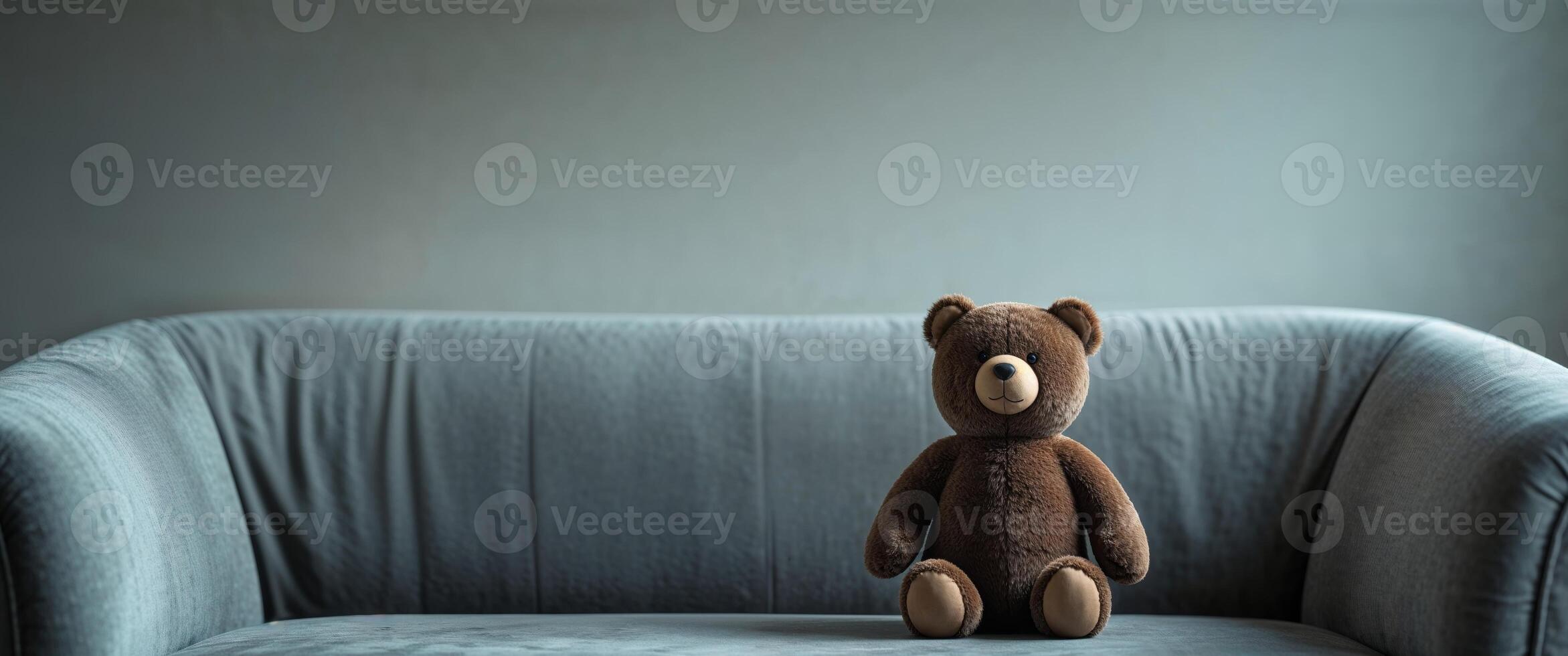 Brown Plush Bear Toy Sitting on Gray Sofa Cozy Home Setting. photo
