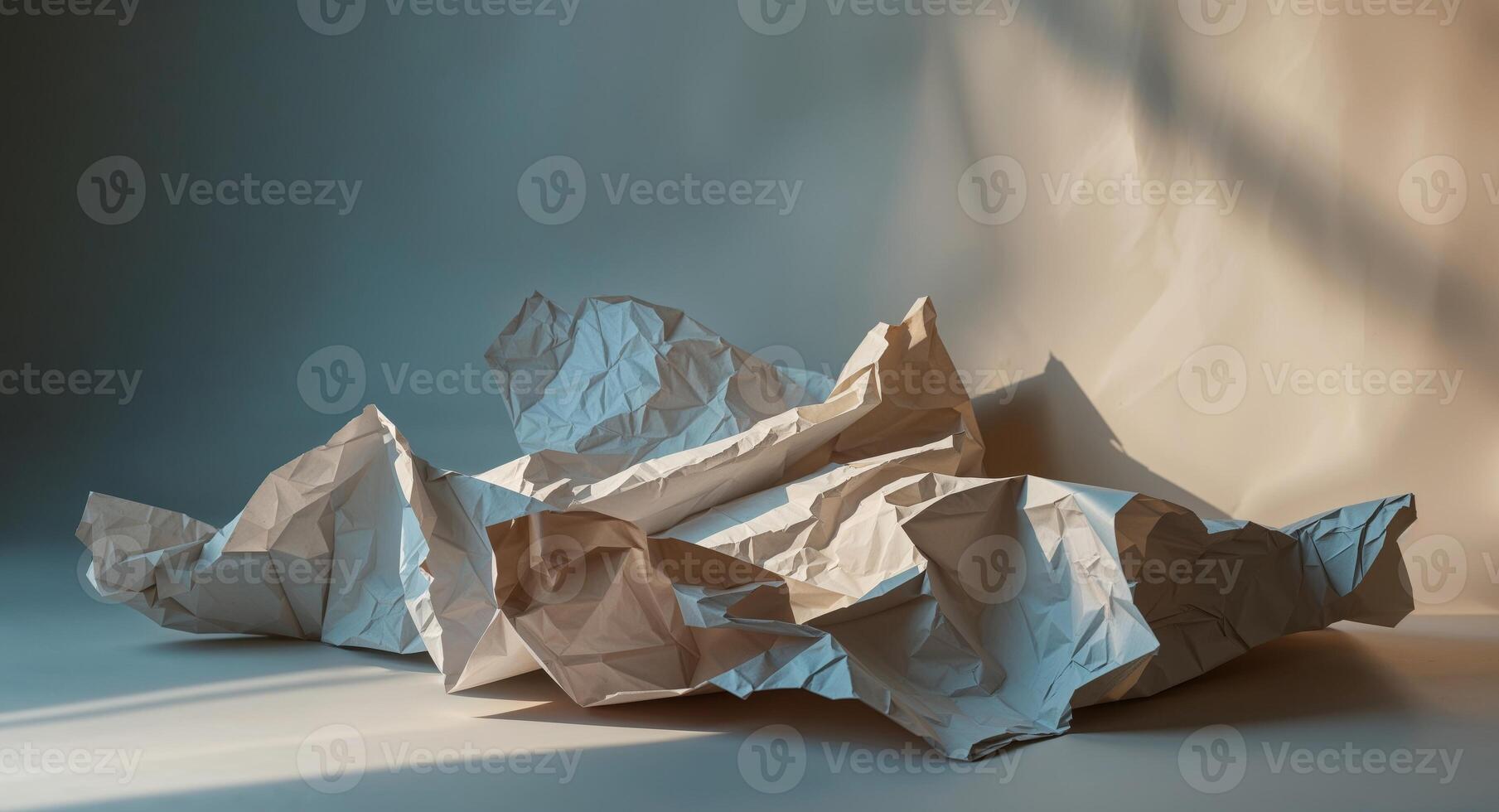 Crinkled paper in shades of blue beige and brown creates a textured and abstract background with deep shadows photo