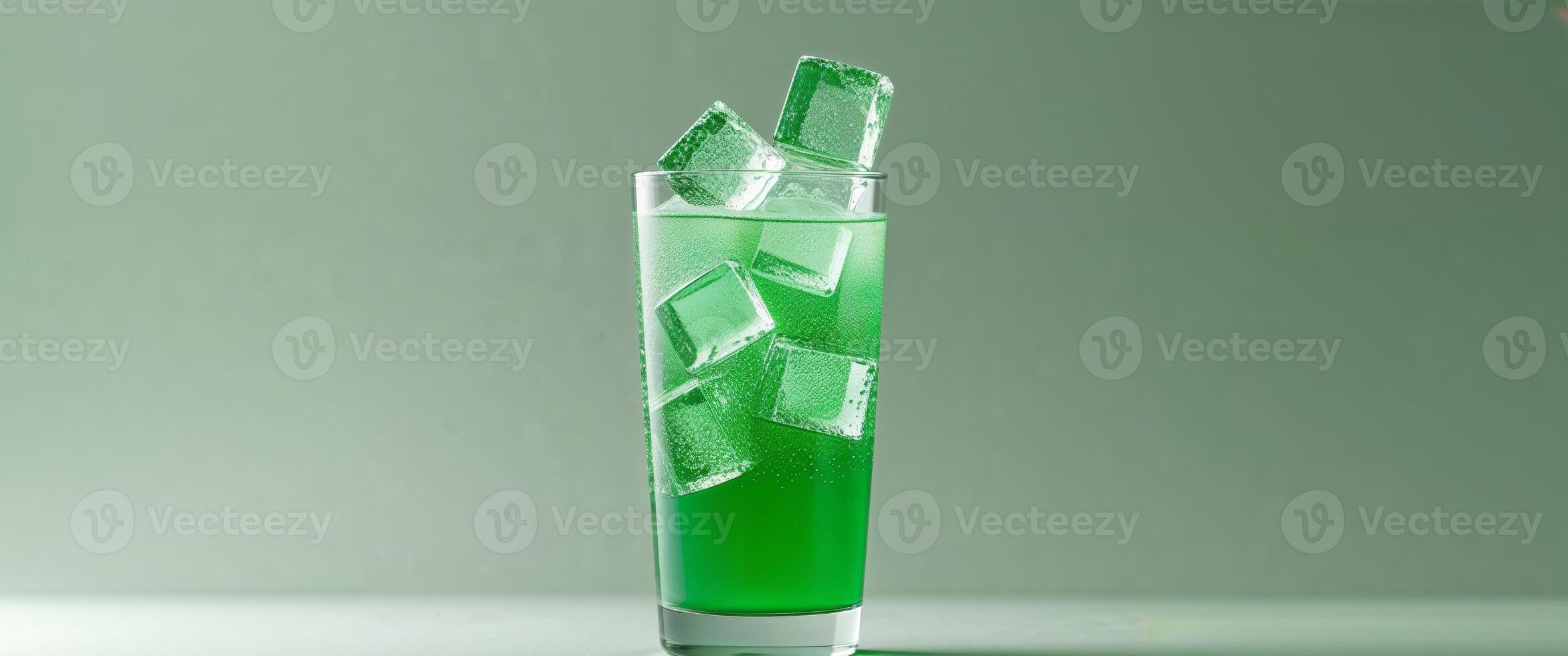 Refreshing Green Beverage with Ice Cubes in a Clear Glass on a Soft Green Background. photo