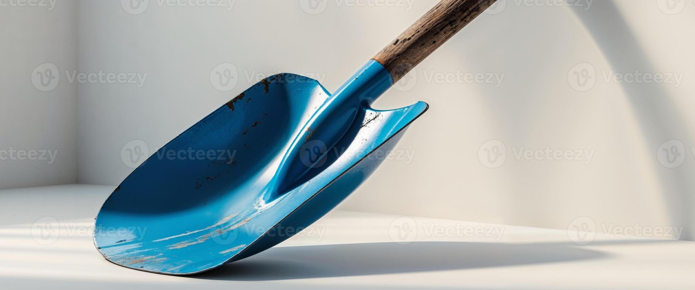 a close up of a blue shovel with a wooden handle. photo