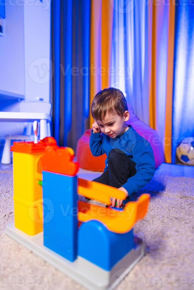 Boy playing with vibrant blocks. A small child engages creatively with vibrant building blocks in a cozy indoor space filled with soft lighting. photo