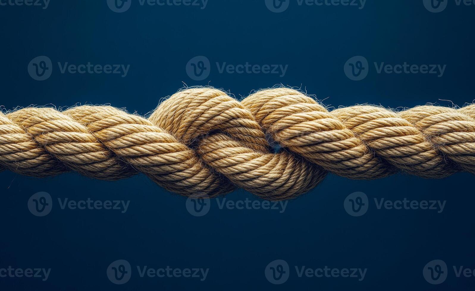 A rope is tied in a knot. The rope is brown and the knot is in the middle of the rope photo