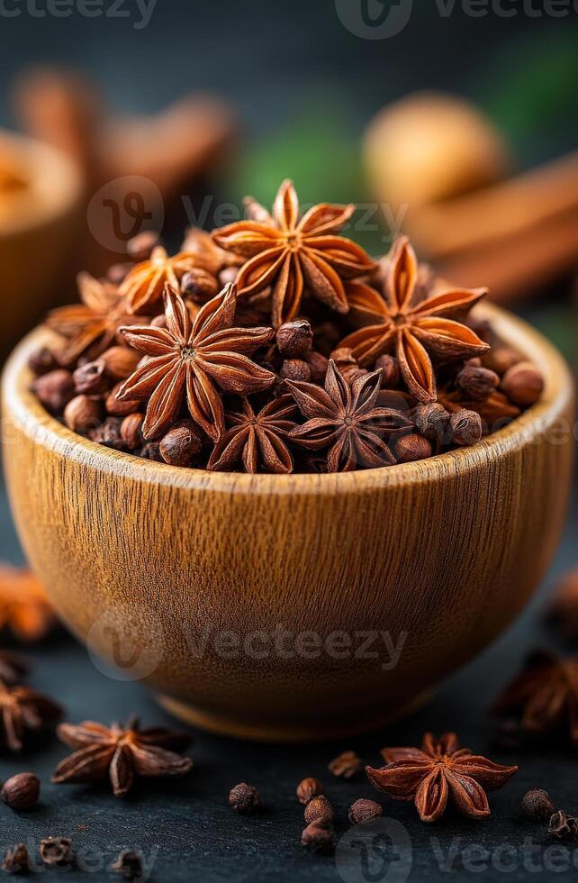 Beautiful bowl of star anise and spices. A wooden bowl filled with vibrant star anise and assorted spices on a dark surface brings warmth and flavor to any dish. photo