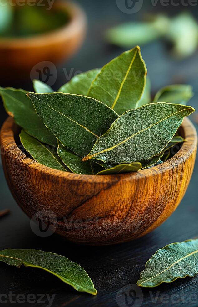 Bay leaves in wooden bowl. Fresh bay leaves are arranged in a rustic wooden bowl, highlighting their vibrant green color against a dark background. photo