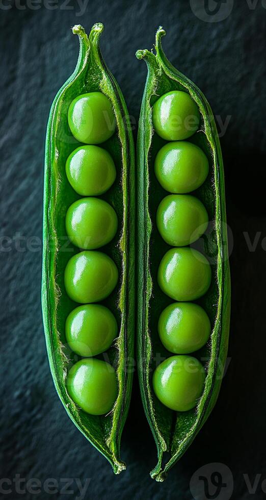 Green peas in pods on dark. Two open pea pods reveal plump green peas nestled inside against a dark background. photo